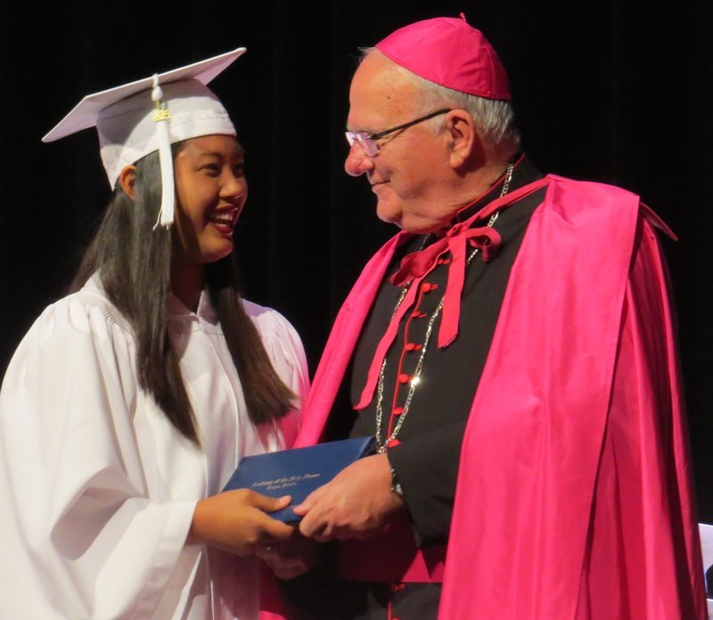 Bishop Lynch and Anna DeGuzman exchange a playful smile while receiving her diploma.