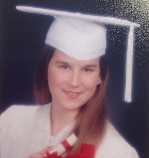 Krukar showing off her soon to be diploma in her senior picture in her cap and gown. 